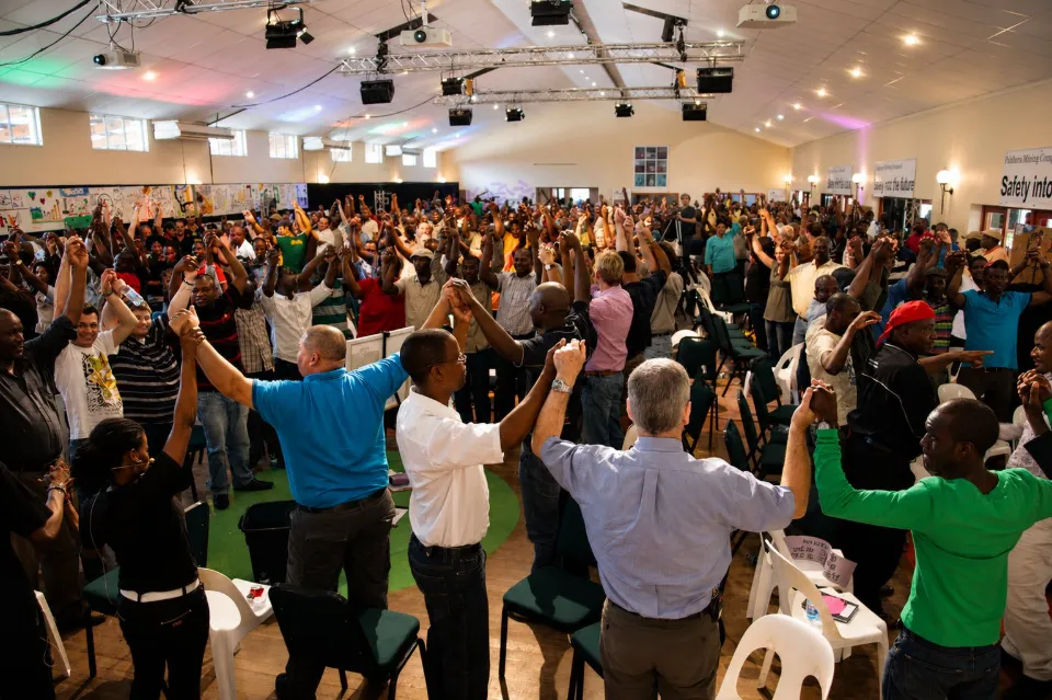 Large group of participants standing with raised arms in a hall