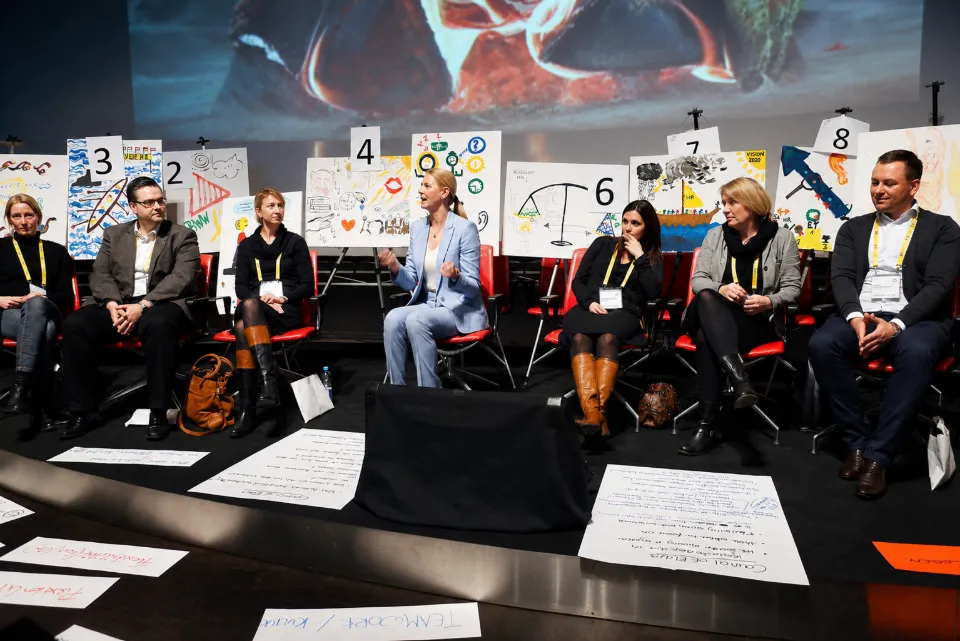 Participants seated in a circle around artworks laid out on the floor